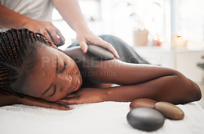Buy stock photo Black woman, hot stone massage, spa with hands of masseuse, holistic and wellness with treatment. Health, peace of mind and zen, self care and rocks, stress relief for people and back skin detox