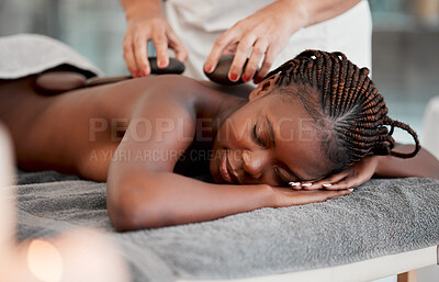 Buy stock photo Black woman, hot stone massage and masseuse, hands and zen with holistic therapy and spa treatment. Calm, peace of mind and female, healing and stress relief with self care at wellness resort