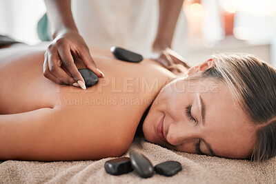 Buy stock photo Woman, hot stone massage and masseuse, hand and zen with holistic therapy and spa treatment for back. Calm, peace of mind and face, healing and stress relief with self care at wellness resort 