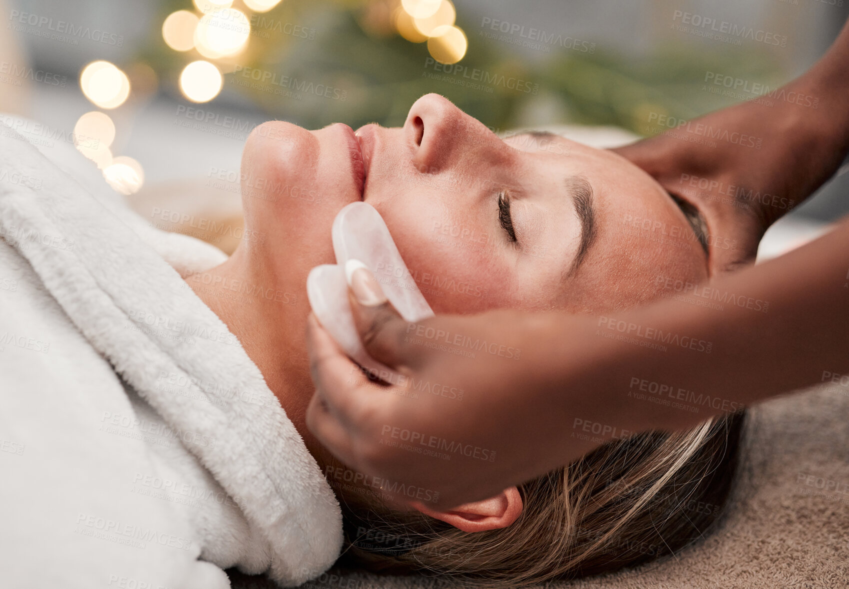 Buy stock photo Beauty, gua sha and woman getting a facial massage for wellness, health and self care at a spa. Skincare, cosmetic and calm young female doing a luxury face treatment with rose quartz at a zen salon.