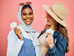 Happy, portrait and lesbian couple with flowers isolated on a pink background in a studio. Smile, looking and Muslim girl with a flower, woman and happiness about plants for romance on a backdrop