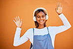 Dance, happy and woman with headphones music isolated on an orange studio background. Smile, free and carefree dancing girl listening to audio, podcast or sound for entertainment and freedom