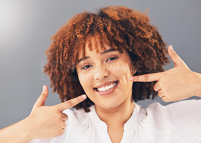 Buy stock photo Portrait, teeth and black woman pointing, excited and dental hygiene against grey studio background. Face, Jamaican female and girl with smile, oral health and gesture to dimples, mouth and wellness