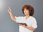 Tablet, pointing and business woman in studio isolated on gray background controlling user interface. Technology, social media and black female entrepreneur with digital touchscreen for web browsing.