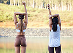 Exercise, stretching and women outdoor in nature for fitness, peace and wellness. Young friends or people warm up at forest lake for workout, training and energy for mental health, chakra and zen