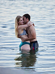 Kiss, hug and couple swimming by the beach for bonding, quality time and holiday by ocean. Romance, happy and man and woman with affection, hugging and enjoying a swim together in the sea on vacation