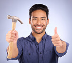 Man, studio and portrait with thumbs up and hammer for handyman, maintenance or repair work with smile. Happy asian model person on purple background for engineer, mechanic or technician job tools