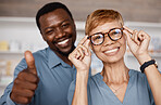 Thumbs up, optometry and woman with glasses for vision or wellness in optics store. Healthcare portrait, hand emoji or smile of happy elderly female with black man or optometrist with success gesture