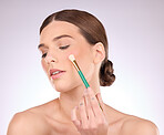 Face, beauty and brush with cosmetics and woman with makeup tools on studio background. Facial, cosmetology and healthy skin glow with color, skincare and hand with foundation shine and elegant 