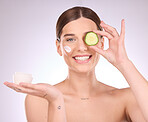 Woman, face and cucumber with moisturizer for skincare nutrition, cream or healthy diet against gray studio background. Portrait of female with vegetable or creme for natural organic facial cosmetics