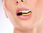 Liquorice, woman eating and mouth with makeup and cosmetics in an isolated studio. White background, sweet food and candy product with hungry female model with cheat meal and sugar for dessert