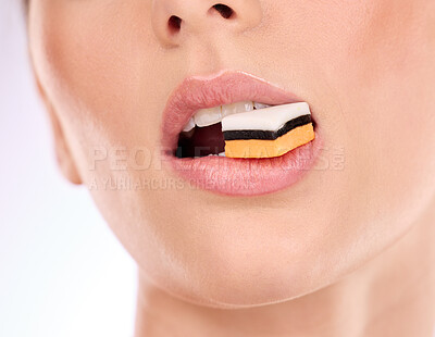 Buy stock photo Liquorice, woman eating and mouth with makeup and cosmetics in an isolated studio. White background, sweet food and candy product with hungry female model with cheat meal and sugar for dessert