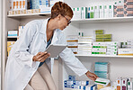 Pharmacist woman, tablet and medicine shelf to check inventory and product information search. Person with pharmacy app in clinic or shop for pharmaceutical, medical and health care consultation