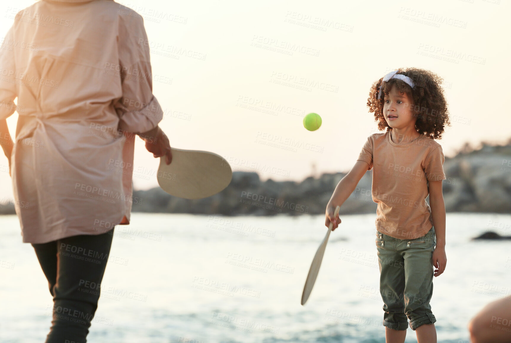 Buy stock photo Family, tennis and girl play at beach, having fun and enjoying holiday or vacation together. Care, sunset and mother playing sports for exercise with kid or child and bonding by ocean or seashore.