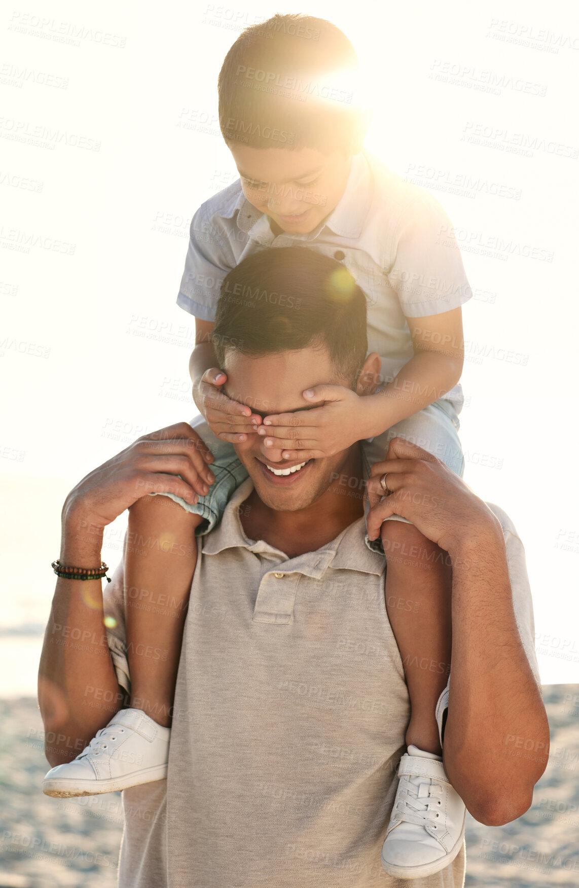 Buy stock photo Beach, travel and child on shoulder of father with hands cover eyes for surprise game, quality time and playing. Family, love and happy boy with dad by ocean bond on adventure, holiday and vacation