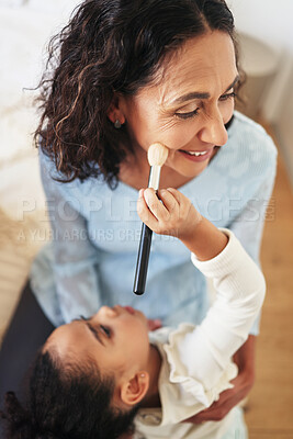 Buy stock photo Playful, happy and child doing makeup of a grandmother for fun, bonding and quality time. Comic, smile and girl with facial cosmetics for a senior woman, playing and applying blush to the face