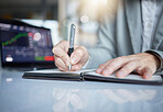 Trader, hands and writing notes by laptop in book on stock market chart or graph statistics for trading at the office. Hand of investor or broker taking note of bitcoin, cryptocurrency or investment