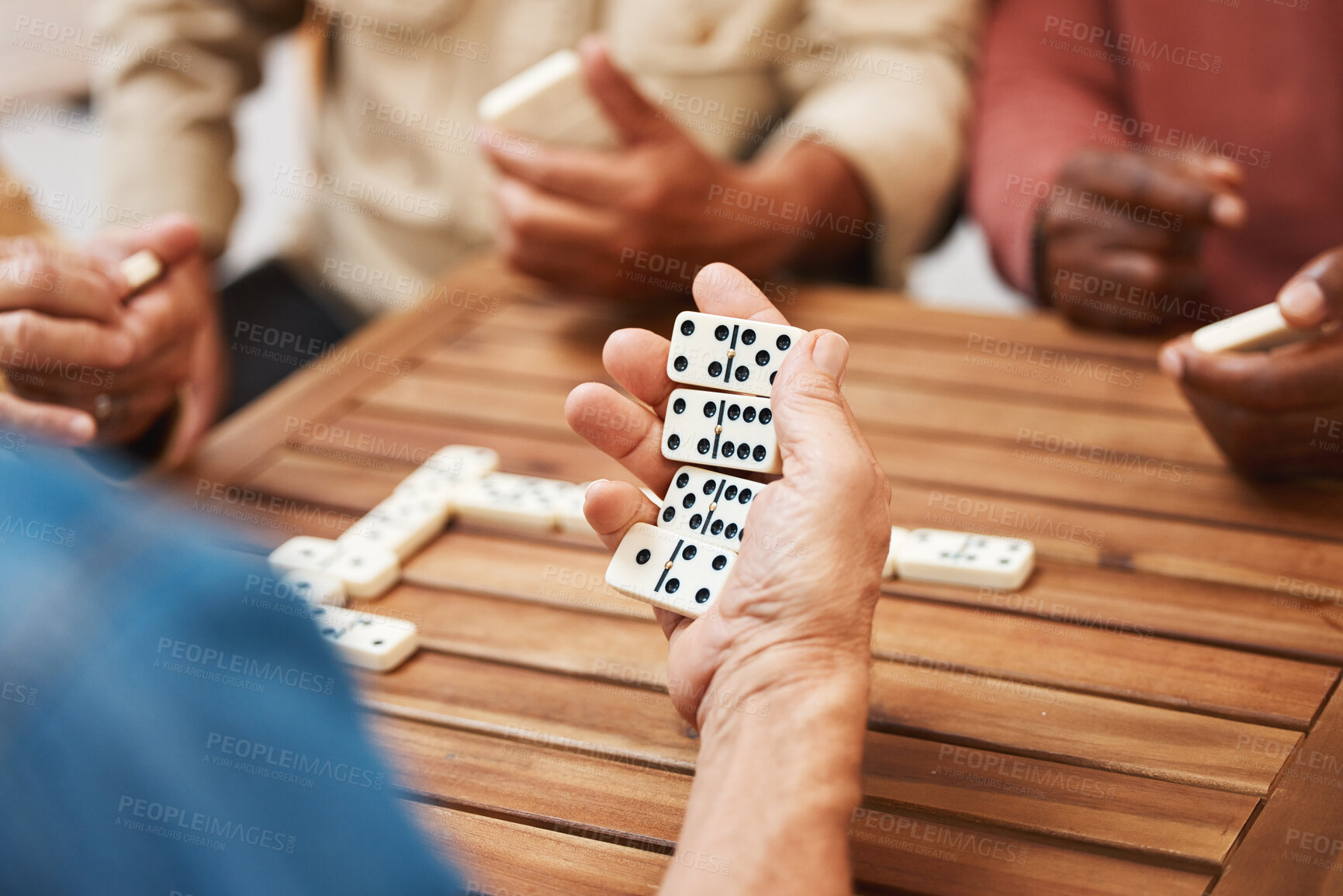 Buy stock photo Hands, dominoes and friends in board games on wooden table for fun activity, social bonding or gathering. Hand of domino player holding rectangle number blocks playing with group for entertainment