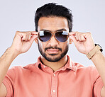 Portrait, sunglasses and man with fashion, trendy and casual clothes against grey studio background. Face, male or gentleman with eyewear, cool or edgy with style, confidence or carefree with success