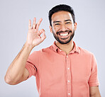 Portrait, hand sign and perfect with a man in studio on a gray background to gesture okay. Emoji, success and good news with a handsome young man indoor to display his approval or agreement