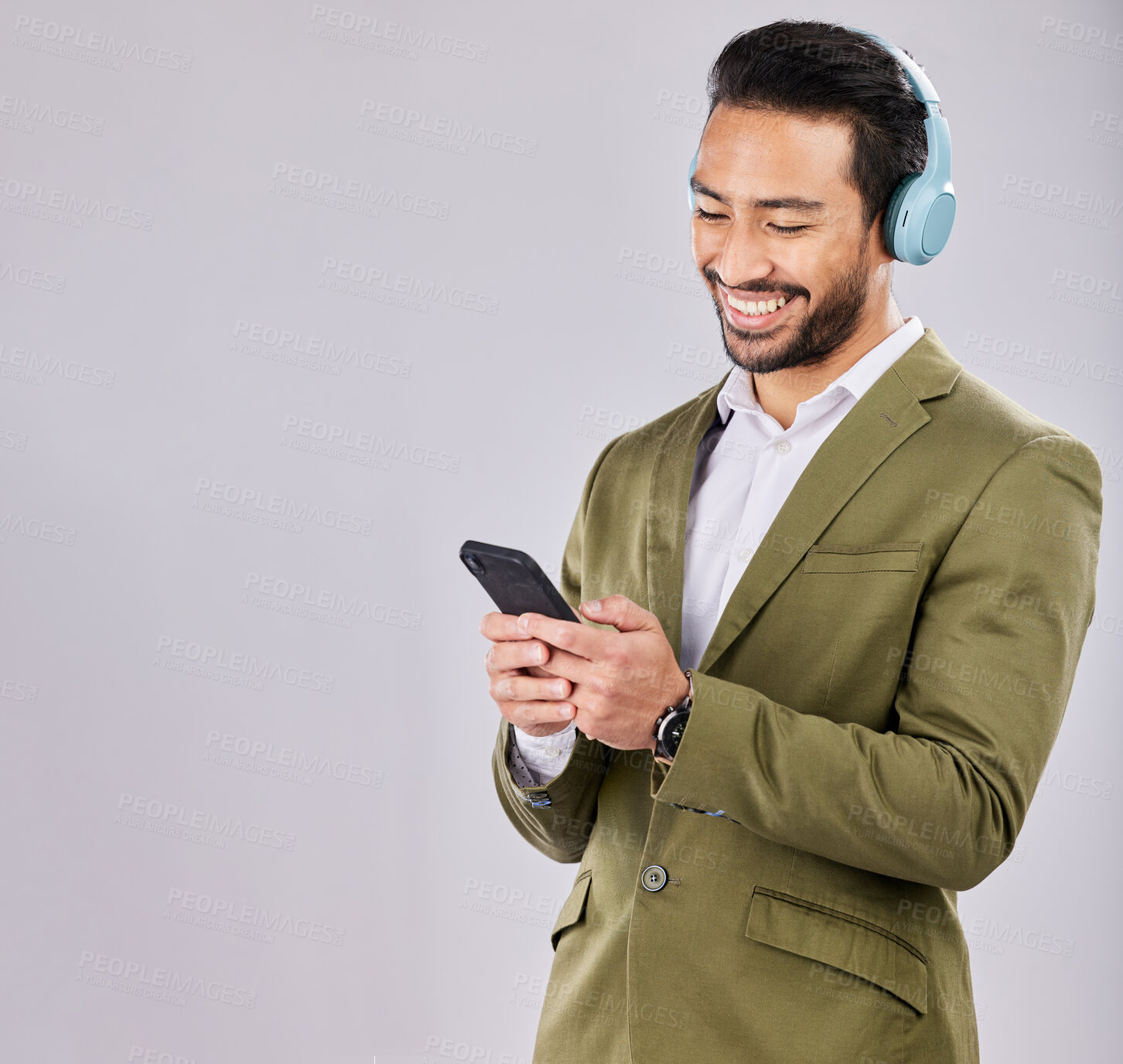 Buy stock photo Asian man, phone and smile in social media with headphones for communication against a gray studio background. Happy formal male smiling on smartphone with headset listening to music on mockup