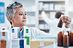 Senior woman, doctor and medicine for healthcare prescription checking stock on shelf in pharmacy. Elderly female pharmacist holding bottle of medication for inspection at drug store or retail clinic