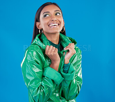 Buy stock photo Gen z, Indian woman and fashion aesthetic of a young female in a isolated studio. Smile, happiness and raincoat for cold weather with blue background and person feeling happy from youth and style