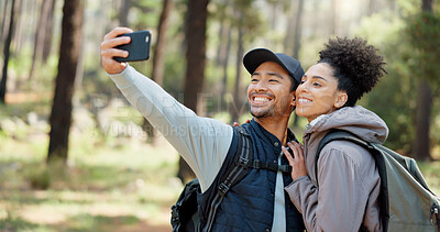 Hiking, selfie and young couple in forest smiling, happy and enjoy nature together. Fitness, wellness and Asian man with black woman taking picture with phone on adventure, trekking and walk in woods