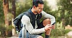 Nature hiking man, typing phone and sitting on rock for rest, break or relax with backpack outdoor. Forest adventure, woods explorer and smartphone for coordinate direction on gps navigation by trees