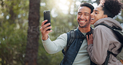 Hiking, walking and young couple in forest on adventure, journey and exploring nature. Asian man and black woman trekking, walk and taking selfie in woods on smartphone enjoying freedom on weekend