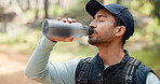 Hike, drinking water and man on a nature walk doing outdoor fitness, exercise and training. Walking, sport and cardio workout of a athlete person from Spain outdoors for wellness, health and sports