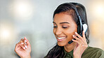 Happy female customer service agent smiling while working in a call centre and talking to a client with a headset. A helpful saleswoman assisting customers with purchase orders and questions online