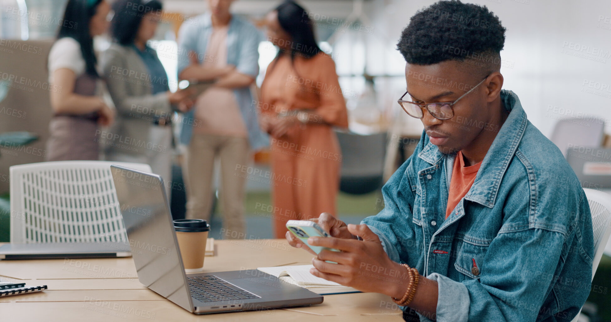 Buy stock photo Black man in office, typing on phone and laptop for market research, email or online report at startup. Creative businessman in coworking space with computer, smartphone and web search at tech agency