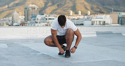 Fitness, sports shoes and athlete in the city preparing for a workout on a rooftop in Mexico. Wellness, health and man tying the laces of his sneakers before a exercise or training in a urban town.