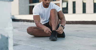Fitness, sports shoes and athlete in the city preparing for a workout on a rooftop in Mexico. Wellness, health and man tying the laces of his sneakers before a exercise or training in a urban town.