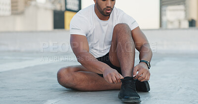 Fitness, man and shoes in sports motivation, exercise or workout for roof top training in the city. Athletic male tying shoe laces ready for cardio wellness, health or sport practice in a urban town