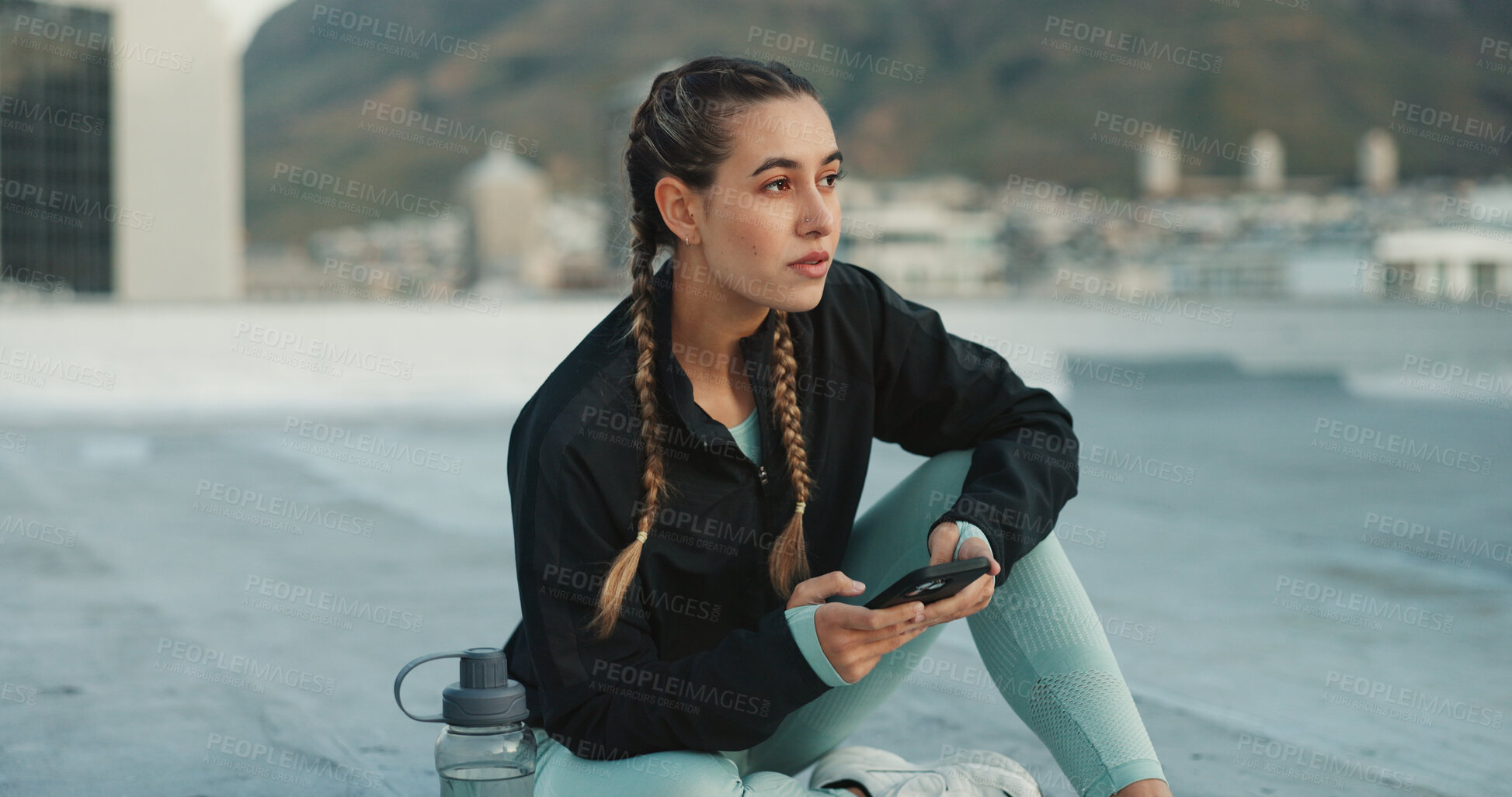 Buy stock photo Social media, fitness and woman with a phone in city for communication, health app and training. Technology, typing and girl thinking of conversation on a mobile app before doing a workout on rooftop