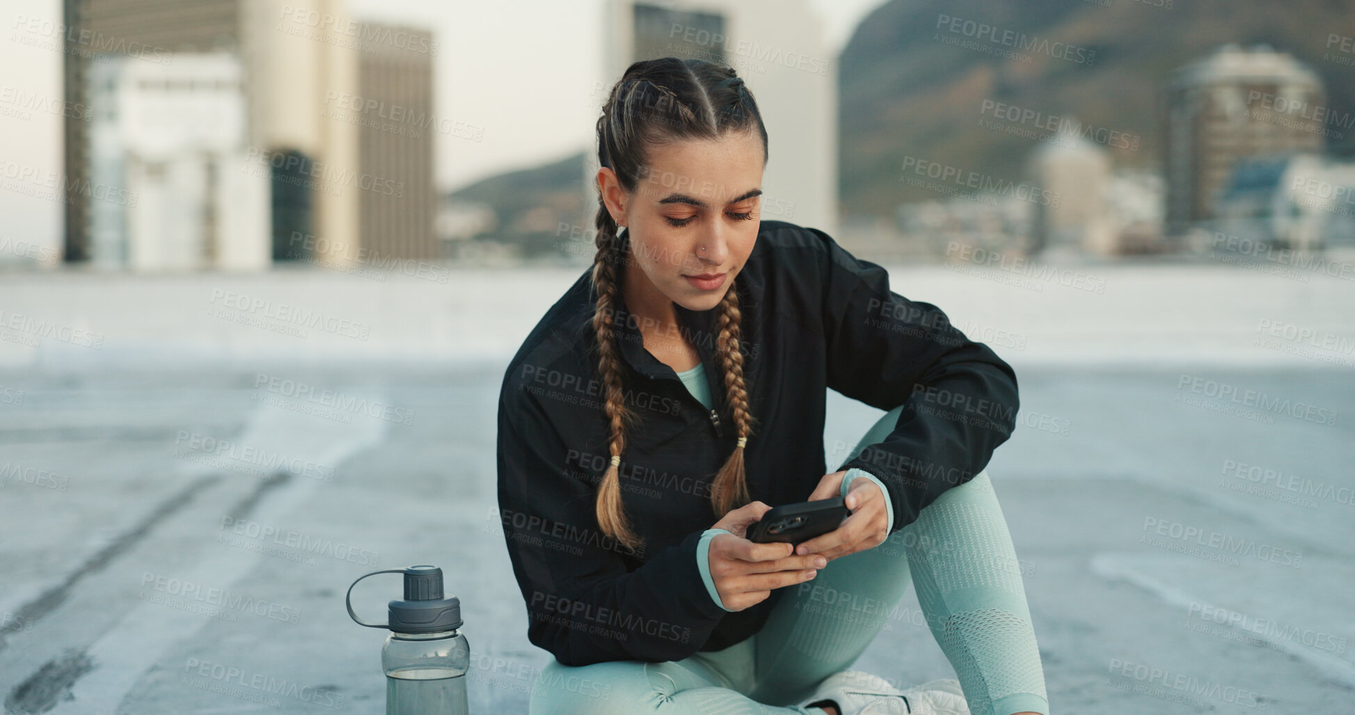 Buy stock photo Phone, exercise and woman on social media in city on a rooftop on workout break outdoor. Fitness, communication and girl athlete networking on the internet with smartphone after cardio training