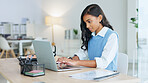 Young woman happily typing on laptop in neat white office doing business. Professional female is attractive and formal with work equipment and stationery around her. Busy emailing or messaging