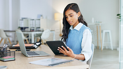 Young business woman using her laptop and tablet while working in the office. Trendy marketing professional using an online app to network, meet deadlines and stay connected during office hours