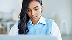 Focused female writer typing on a laptop while working on a new headline article or thought piece in an office. Trendy young journalist or online blogger writing project ideas and working in office