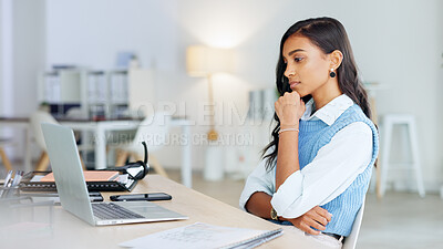 Trendy business woman using laptop and thinking of ideas while working on a project in her office. Young journalist or female entrepreneur working on her blog and trying to find inspiration online