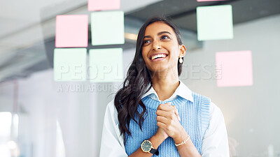Young business woman brainstorming and planning a mind map with ideas on sticky notes on a glass wall in an office. One focused designer thinking while analyzing a marketing strategy with solutions