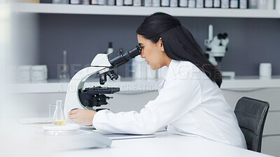 Young scientist using a digital tablet and microscope in a lab. Female pathologist analyzing medical samples while doing experiments to develop a cure. Microbiologist conducting forensic research