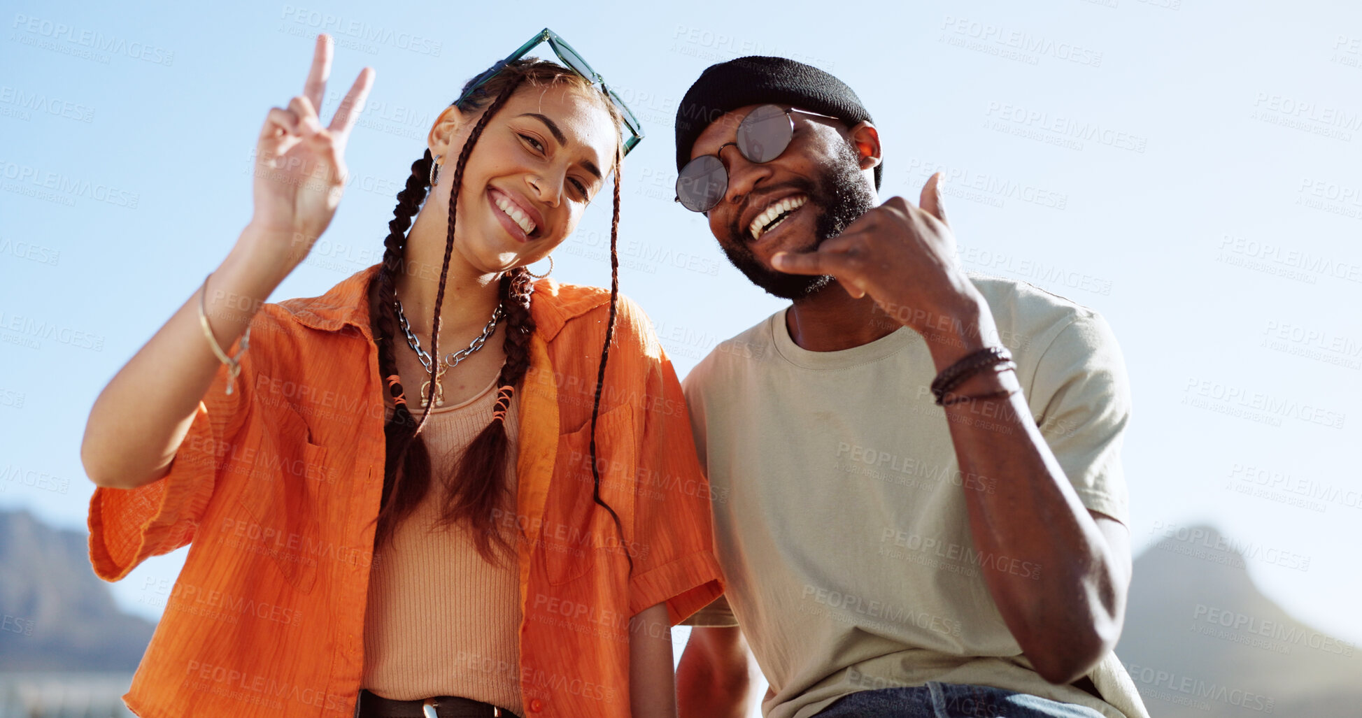 Buy stock photo Couple of friends, rooftop and city portrait, emoji and youth in happy social bonding with summer sky. Relax, gen z man and woman sit on roof with smile, peace sign and shaka on urban date together.