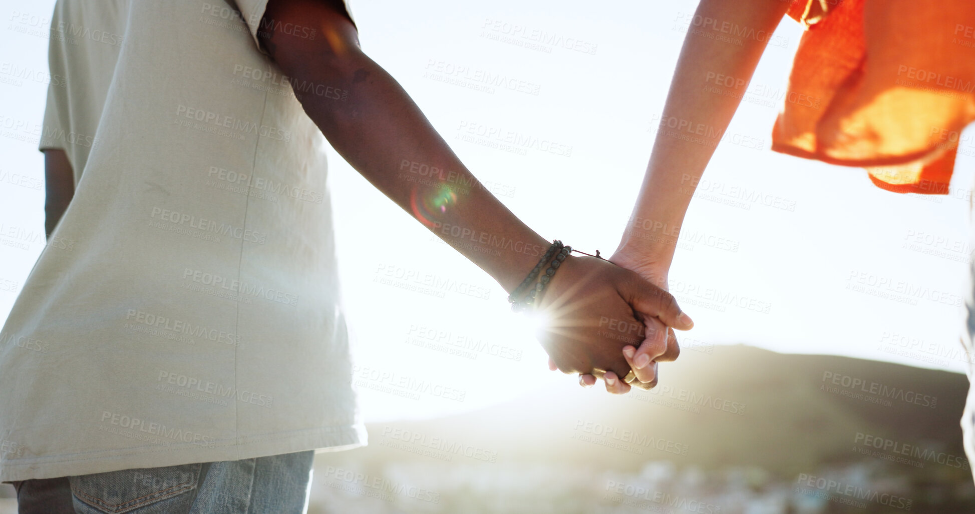 Buy stock photo Holding hands, love and flare with an interracial couple on the beach at sunset for romance or dating. Nature, freedom or relax with a man and woman closeup on the coast together for holiday travel