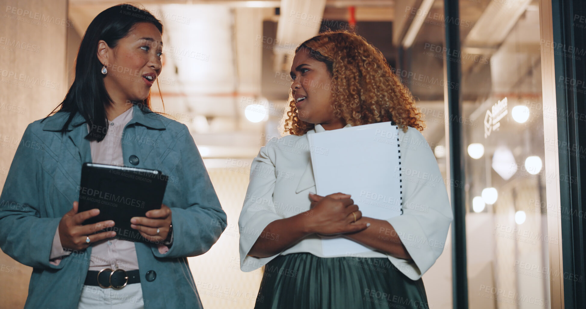 Buy stock photo Tablet, collaboration and business women walking in the office together while planning or talking at night. Technology, documents and diversity with an employee team in discussion at the workplace