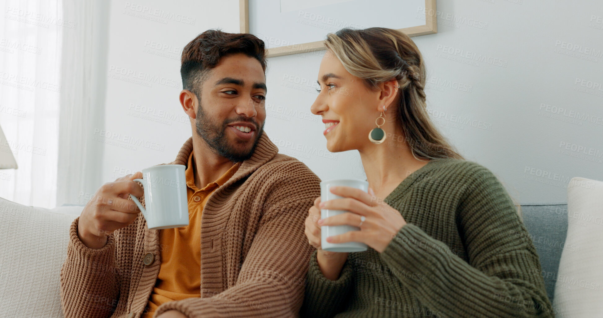 Buy stock photo Couple, coffee and sofa for conversation or communication for bonding or happiness or relaxing for smile. Interracial people, living room and talking for fun on couch for relaxing, love or discussion