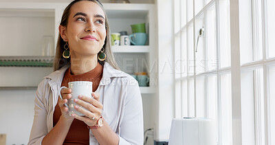 Beautiful woman looking out window holding cup of coffee