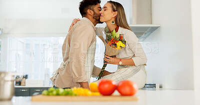 Couple love, flowers and happy cooking together in kitchen at home, romance and celebrate relationship bonding. Married man and woman smile, surprise bouquet and happiness care in family house